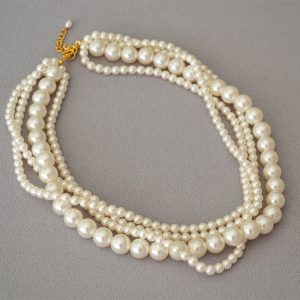 A multi-layered necklace with large and small pearls intertwined.